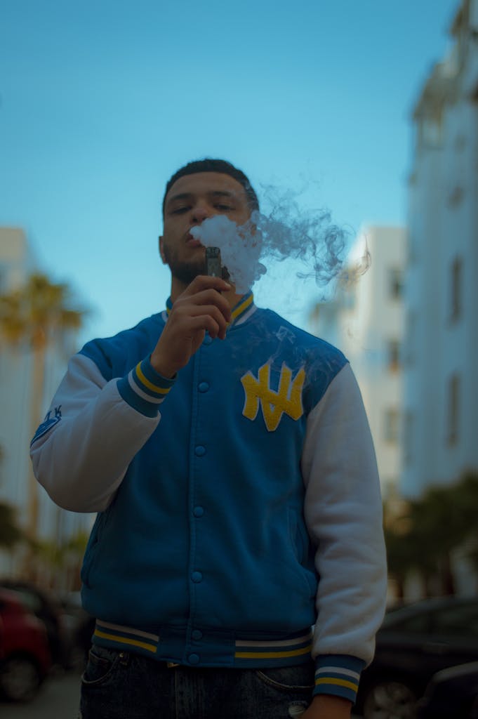 A young man in a varsity jacket vapes on a street in Casablanca, Morocco.