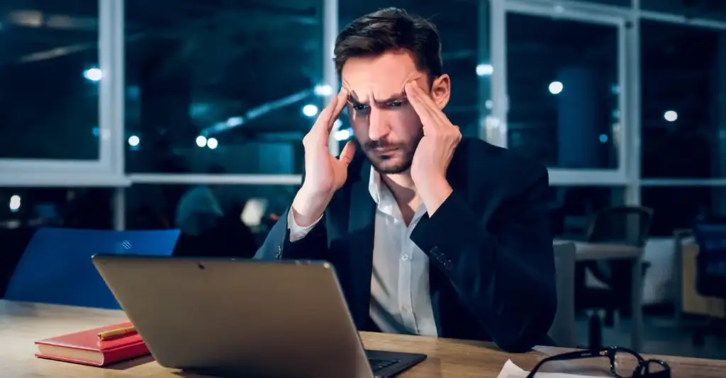 Exhausted businessman struggling with work stress due to alcohol addiction affecting job performance