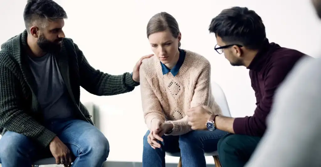Woman receiving emotional support during alcohol rehab group therapy session