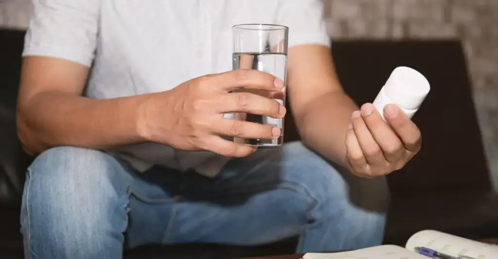 Elderly person holding prescription pills and a glass of water, showing medication use and potential drug dependency